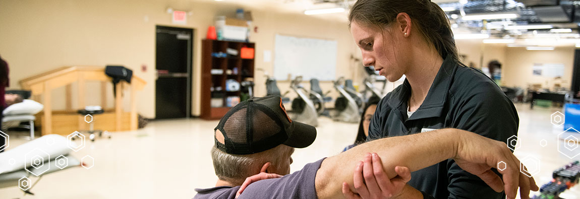 A University of Lynchburg Doctor of Physical Therapy (DPT) student helping a patient with an arm exercise