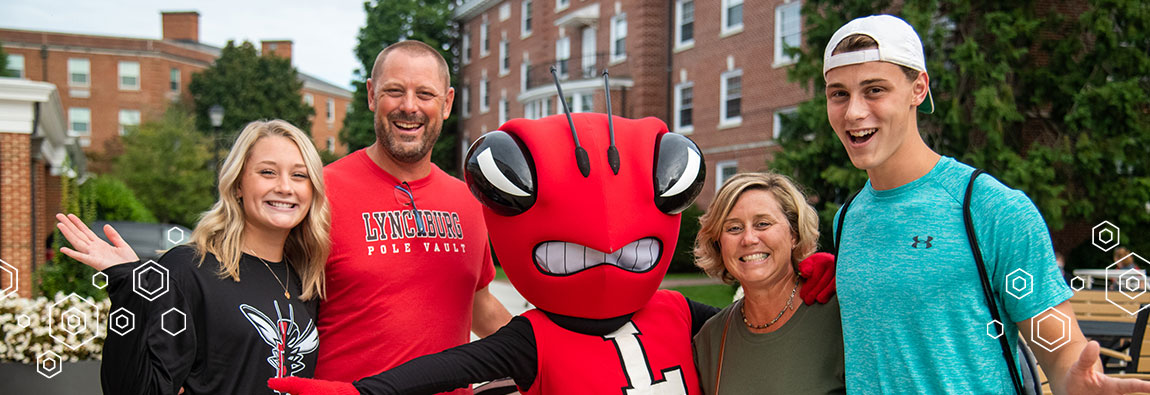A happy family of four people posing with the University of Lynchburg's mascot: a red hornet